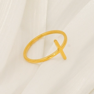 Minimalist golden cross ring with adjustable open band on white satin background