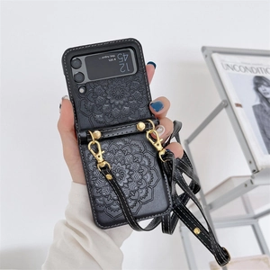 Detail of black mandala embossed leather phone case with gold metal strap buckles