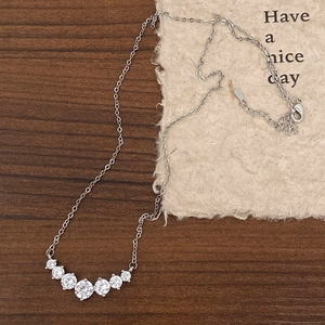 Detailed close-up of a silver smiley face necklace with sparkling zircon on wood background