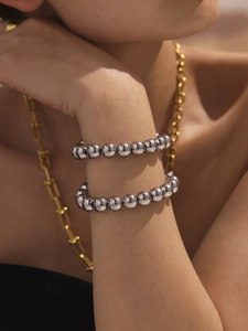 Close-up of stacked silver stainless steel bead bracelets with a polished finish