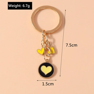 Close-up of golden keychain with yellow hearts and black pendant showing 7.5cm length