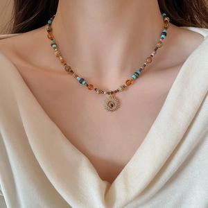 Tiger eye sun pendant necklace with boho beads worn on a model's collarbone