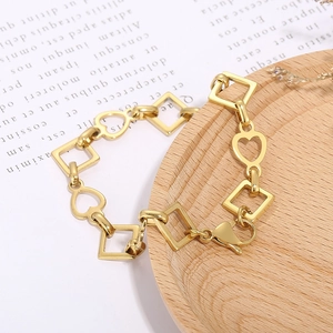 Detail view of golden heart and square chain links on a light wooden background