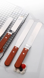 Close-up of a stainless steel offset spatula with a durable rosewood handle and rivets