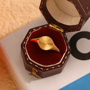 Detailed view of an 18K gold plated sunburst engraving ring in a red velvet jewelry box