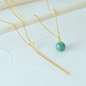 Detail of 925 silver gold chain necklace with turquoise bead and small diamond on white branch