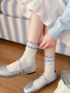 Détail de chaussettes en coton crème avec bords à volants et liseré bleu en Mary Janes