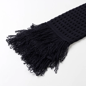 Detailed macro view of black knit fabric featuring mesh hollow-out and long fringe trim