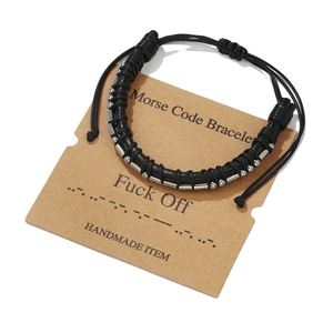 Detail view of leather Morse Code bracelet with metal beads on a kraft paper gift card