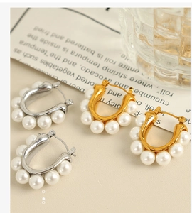 Close-up of U-shaped gold and silver earrings with elegant white pearls for women