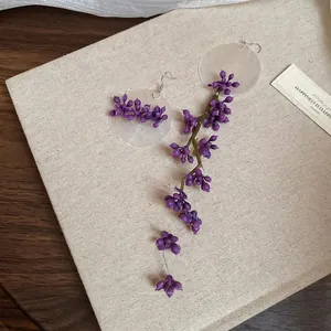 Asymmetric purple flower tassel earrings on canvas board with artistic wood background