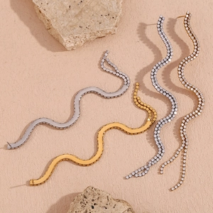 Detail of gold and silver S-curve wave earrings with polished finish and pavé zircon stones
