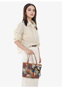 Close-up of geometric color block tote bag with brown handles and decorative silk scarf