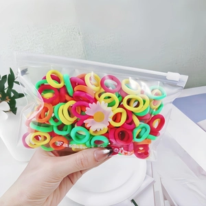 Close-up of assorted colorful small cotton elastic hair ties in a clear zipper bag