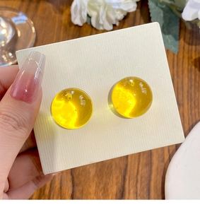 Macro detail of vibrant yellow round resin stud earrings with a clear bubble texture