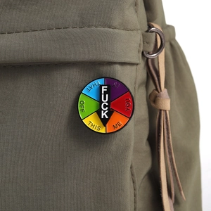 Close-up of a rotating rainbow enamel pin with a black arrow on a canvas backpack