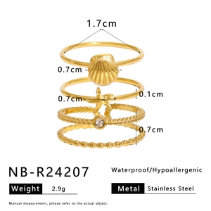 Detail of four-piece gold marine ring set with starfish and shell designs in stainless steel