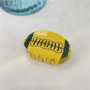 Detailed view of yellow American football hair claw clip with black and green stitching