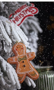 Close-up of gingerbread man ornament on a snowy Christmas tree with Merry Christmas text
