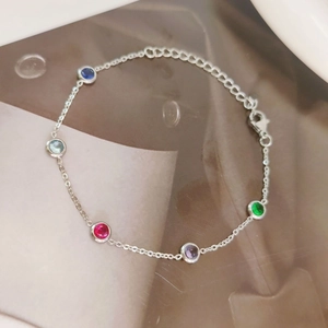 Gold-plated necklace with colorful round-cut zirconia crystals on textured background