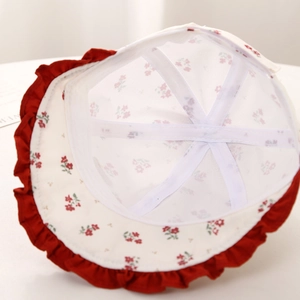 Dettaglio di cappello da sole per neonati con fodera in rete e tesa floreale a onde rosse