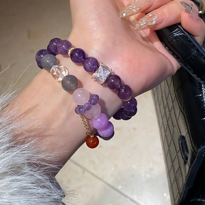 Detail of amethyst and agate bead bracelets with crystals on a woman's wrist