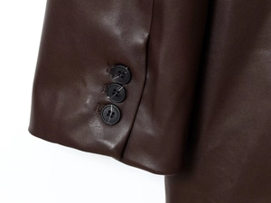 Detailed close-up of dark brown faux leather jacket cuffs with three black buttons