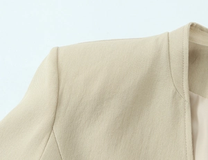 Detailed close-up of beige blazer shoulder with fine fabric texture and premium stitching