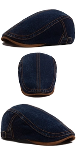 Detailed view of denim flat cap showing vintage metal buckle and orange double stitching