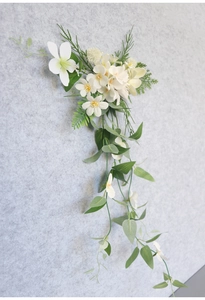 Detailed close-up of white silk flowers and green plastic vine wall hanging decor