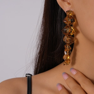Detail of amber geometric acrylic drop earrings on model with natural lighting focus