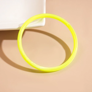 Detailed close-up of a translucent fluorescent yellow-green acrylic resin bangle on beige