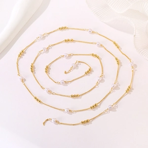 Detail of a long gold chain with white heart beads and small gold spheres in a spiral layout