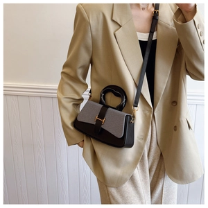Close-up of contrast color box bag with gold H-buckle on elegant beige suit outfit