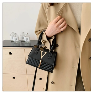 Close-up of black leather handbag with gold V-metal logo and elegant fringe detail