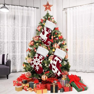 Set of three embroidered plush Christmas stockings hanging on a festive tree.