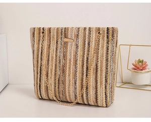 Detail of colorful woven straw bucket bag with golden chain strap and textured stripes