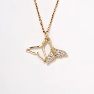Detail view of gold whale tail pendant with sparkling pavé cubic zirconia accents