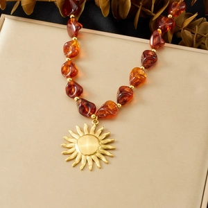 Détail du collier pendentif soleil doré vintage avec perles ambrées de forme irrégulière
