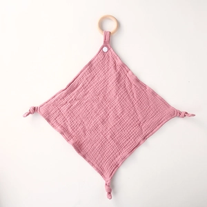 Detailed view of a pink cotton muslin baby security blanket with a wooden teething ring