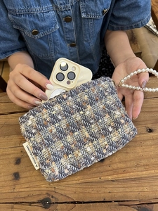 Macro shot of a tweed weave pouch showing a large smartphone fitting into the storage bag