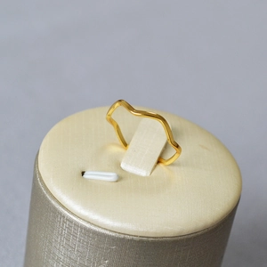 Anello a onda minimalista placcato oro su supporto con illuminazione morbida