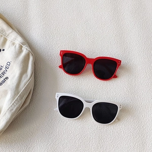 Flat lay of red and white thick-frame sunglasses with metal rivets on woven background