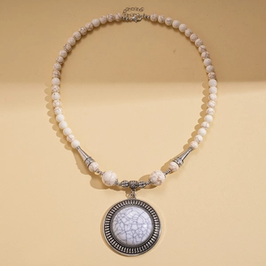Detail of bohemian stone beads and large round vintage pendant with embossed metal pattern