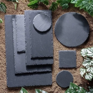 Set of dark gray natural slate dinner plates in various shapes on a rustic background