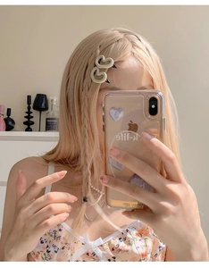 Détail de pinces à cheveux doubles cœurs crème portées sur une tresse dans un décor de vie
