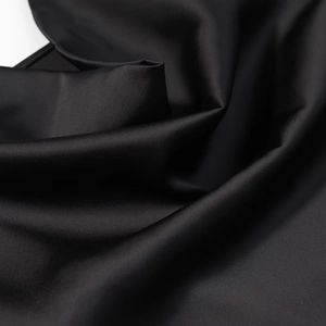 Gros plan sur le tissu en satin de soie noir montrant une texture lisse et des drapés doux