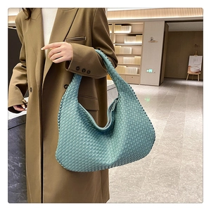 Close-up of a blue woven hobo shoulder bag with professional artisanal braiding texture