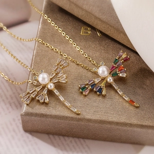 Gold-plated dragonfly necklace with zircon wings and white pearls on a jewelry box