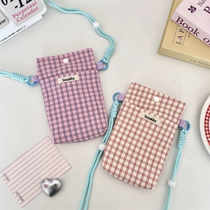 Detail view of checkered crossbody phone bags with woven rope straps and button closures